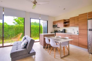 A modern kitchen with wooden cabinets, a built-in microwave, and a stainless steel refrigerator. - Captivating 2-bed Apartment (Jacó)