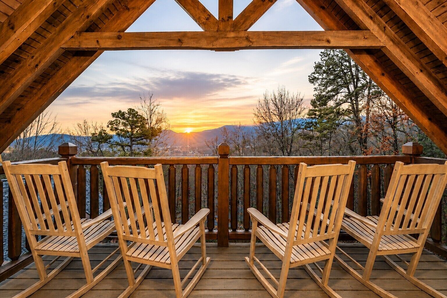 Una terraza de madera con tres mecedoras orientadas hacia una vista panorámica del atardecer sobre montañas.