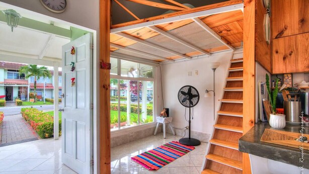 A modern interior with a wooden staircase, a fan, and a view of the outside. - Romantic Tiny Apartment (Jacó)