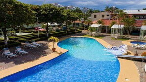 A swimming pool with lounge chairs and a small palm tree. - Romantic Tiny Apartment (Jacó)