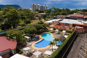 Ein Hotel mit Schwimmbad, umgeben von Grünflächen und Gebäuden.
