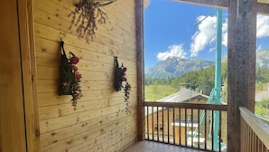 Een houten interieur met een balkon met uitzicht op een bergachtig landschap.