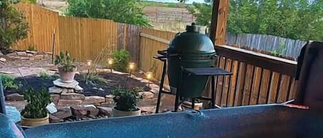 Una vasca idromassaggio con un pontile in legno, un barbecue e un cortile recintato.