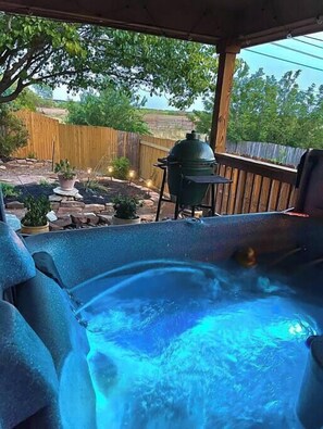 Ein Whirlpool mit Holzterrasse und einem Grill im Hintergrund.