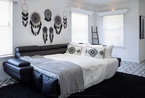 A modern bedroom with a bed, a bench, and wall decor. - 🌵 Stylish Hot Tub Oasis 🌵 (San Antonio)