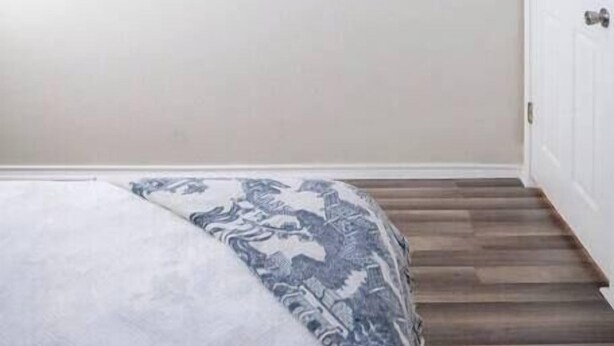Une chambre à coucher comprenant un lit, un ventilateur de plafond, un téléviseur fixé au mur et une armoire.