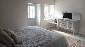 Ein Schlafzimmer mit Bett, Kommode, Fernseher und Fenster.
