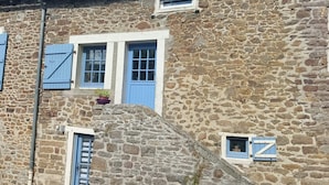 Ein Gebäude aus Stein mit blauen Fensterläden, einem kleinen Fenster und einem Blumentopf.