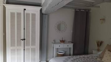 A bedroom with a bed, a bedside table, a mirror, and a wardrobe.