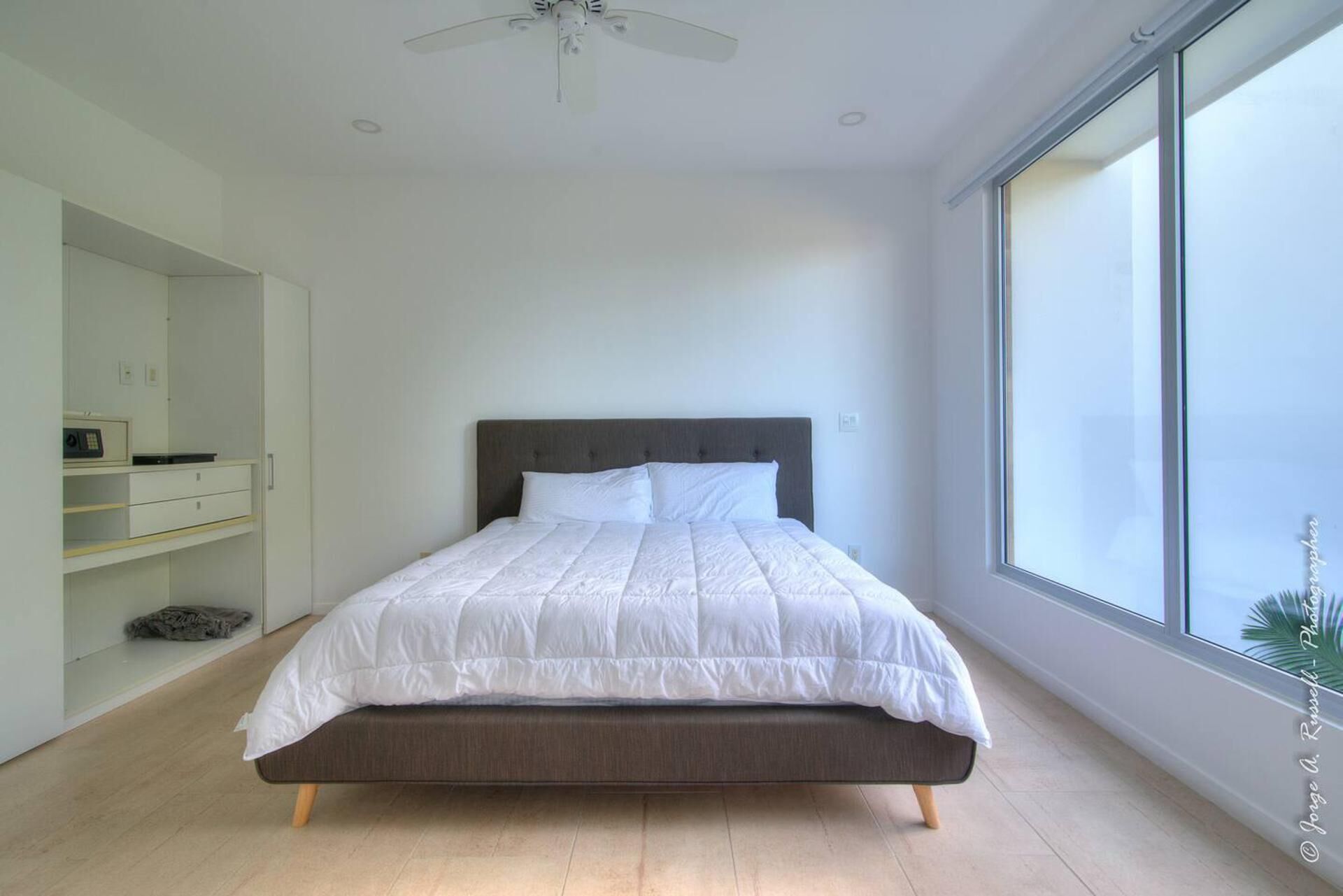 A modern bedroom with a large bed, a wardrobe, and a window with a view.