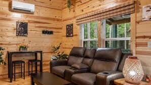Una habitación acogedora de estilo cabaña con un sofá de cuero, una mesita pequeña y una zona de bar.