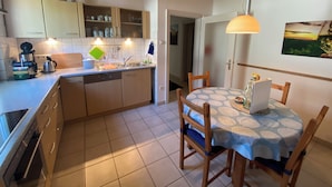 Una cocina con armarios de madera, un lavamanos y una mesa de comedor con sillas.