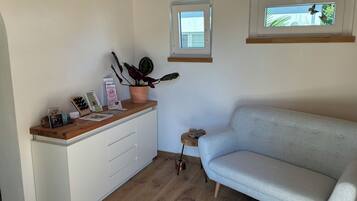A room with a sofa, a wooden counter, a potted plant, and a window.