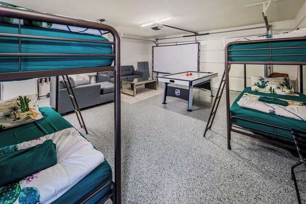 Een slaapkamer met stapelbedden, een bureau, een stoel, een tafelvoetbaltafel en een whiteboard.