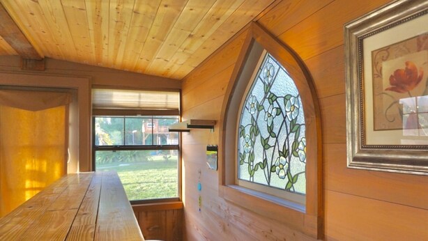 A wooden interior with a large table, a window with a stained glass design, and a framed picture on the wall. - With tree house, Surprising Tropical-style resort (St. Cloud)