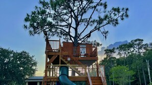 A playground with a slide, a climbing structure, and a fenced area. - With tree house, Surprising Tropical-style resort (St. Cloud)