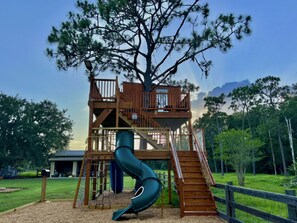 A playground with a slide, a climbing structure, and a fenced area. - With tree house, Surprising Tropical-style resort (St. Cloud)