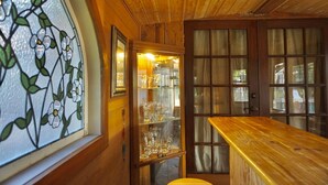 A wooden interior with a glass door leading to a room containing a bar area with glasses and bottles. - With tree house, Surprising Tropical-style resort (St. Cloud)