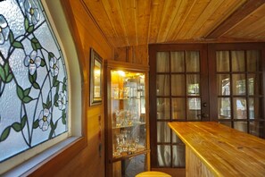 A wooden interior with a glass door leading to a room containing a bar area with glasses and bottles. - With tree house, Surprising Tropical-style resort (St. Cloud)