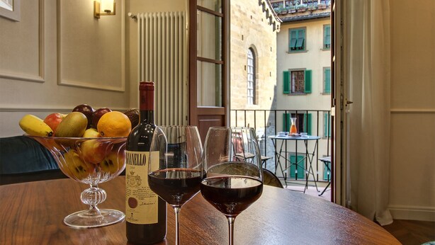 Une table avec une bouteille de vin, deux verres de vin et un saladier de fruits.