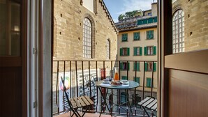 Un balcon avec une table dressée pour deux personnes, une chaise et une bouteille de jus d’orange.