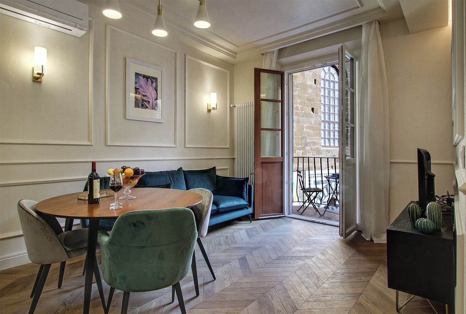 Zona pranzo con tavolo rotondo, sedie, divano e balcone con vista.