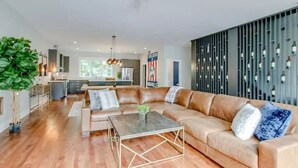 Ein geräumiges Wohnzimmer mit einer großen Eckcouch, einem Couchtisch und einer Küche im Hintergrund.