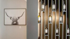 Eine Wand mit einem gerahmten Kunstwerk von einem Stierkopf und einem Weinregal mit Flaschen.