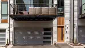 Ein modernes, zweistöckiges Haus mit Balkon, großen Fenstern und Garage.