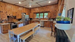 Una cocina con armarios de madera, una mesa de comedor de madera y una planta colgante.