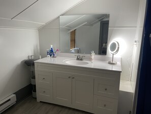 A bathroom with a white vanity, a large mirror, and a sink. - Historic Skye House in the Heart of Northport (Northport)