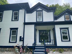 A two-story house with a front porch, a stone foundation, and a bicycle parked outside. - Historic Skye House in the Heart of Northport (Northport)