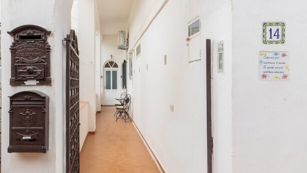 Un couloir aux murs blancs, doté d’un sol carrelé et d’une porte au fond.