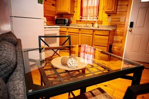 A modern kitchen with wooden cabinets, a microwave, and a glass dining table with a woven placemat.