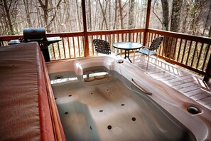 A hot tub on a wooden deck with a view of trees.