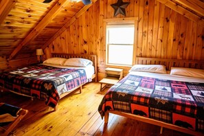 A cabin with two wooden beds, a star decoration, a window, and a wooden floor.