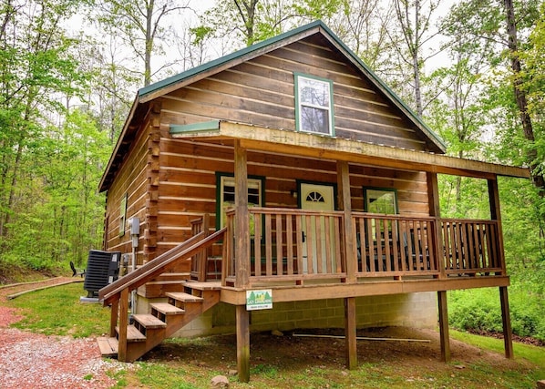 A cabin with a porch, a staircase, and a sign indicating 'Lazy Lake Greens Bear Hollow.'