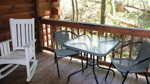 Une terrasse en bois avec une table en verre et deux chaises.