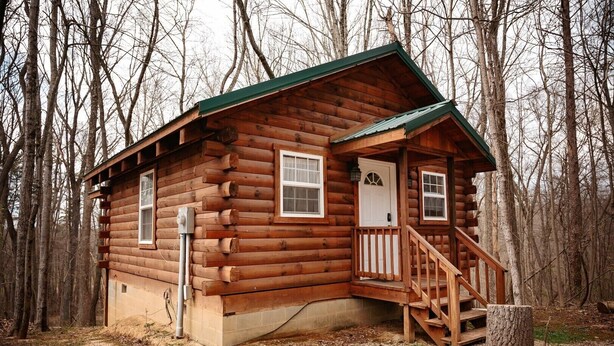 Une cabane en rondins avec un porche et un escalier.
