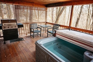 A wooden deck with a hot tub, a grill, and outdoor furniture.