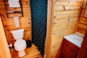A wooden bathroom with a toilet, sink, and towel rack.