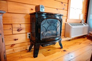 A wood-burning stove with a digital thermostat, a white air conditioner, and a wooden floor.