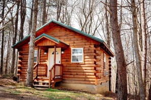 A log cabin with a porch, a door, and a window. - Welcome to Acorn Ridge! (Logan)