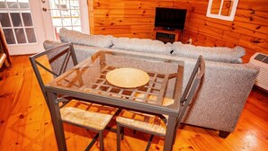 A glass-top table with woven chairs in a wooden interior. - Lazy Lane Cabins - Buckeye (Logan)