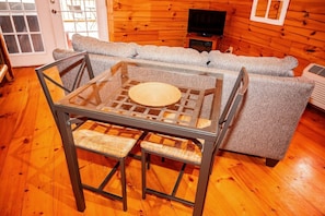 A glass-top table with woven chairs in a wooden interior. - Lazy Lane Cabins - Buckeye (Logan)