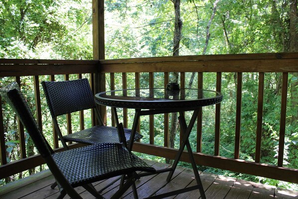 Guests can enjoy a tranquil outdoor space with a scenic view from this deck, featuring a round table and two chairs.