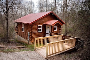 A log cabin with a wooden deck and a metal roof. - Lazy Lane Cabins - Buckeye (Logan)