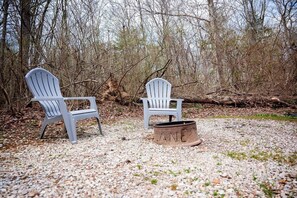 Dos sillas Adirondack y un brasero en un entorno natural.