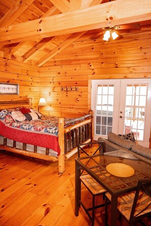 A log cabin interior with a bed, a table, and a sofa.