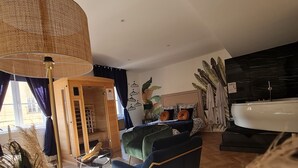 A modern living room with a large window, a sofa, a lamp, and a kitchen area with a sink. - Spa, sauna, tropical rain sky, complimentary bottle, romantic night  (Macon)